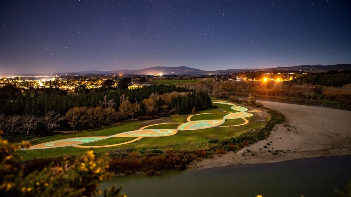 Aerial view of illuminated pathway alongside the river.